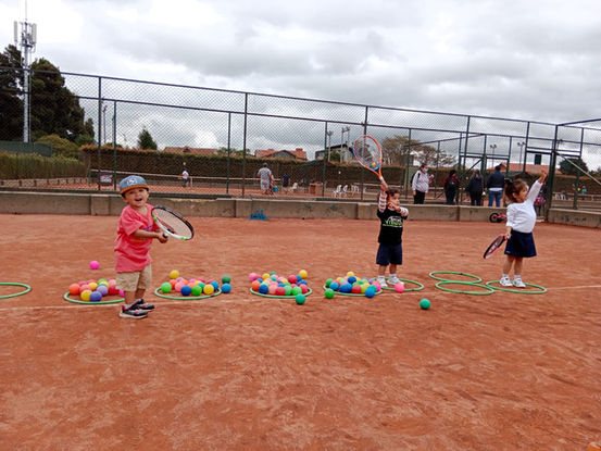 Niños entrenando en la cancha de tenis